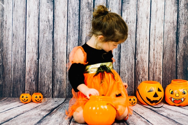 Free photo little girl amidst pumpkins