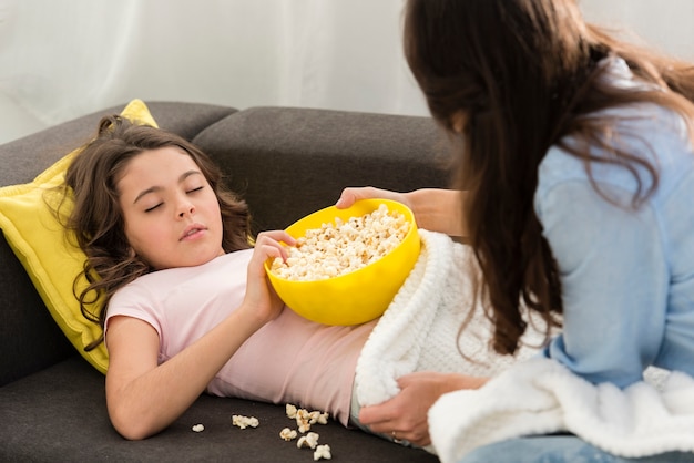 Free Photo little girl being sleepy with a bowl of popcorn