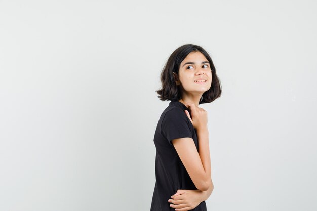 Little girl in black t-shirt looking back over her shoulder and looking curious .