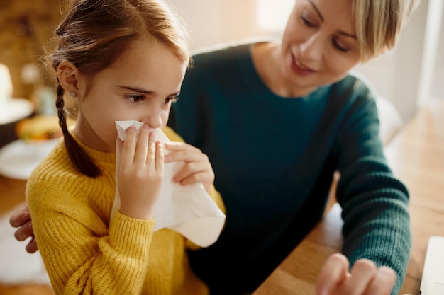 Free photo little girl blowing nose while being with her mother at home