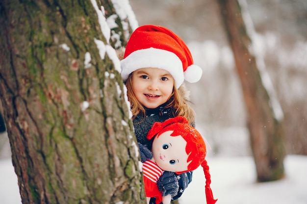 Little girl in a blue hat playing in a winter forest