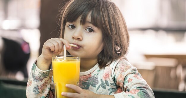 Little girl in a cafe drinking juice