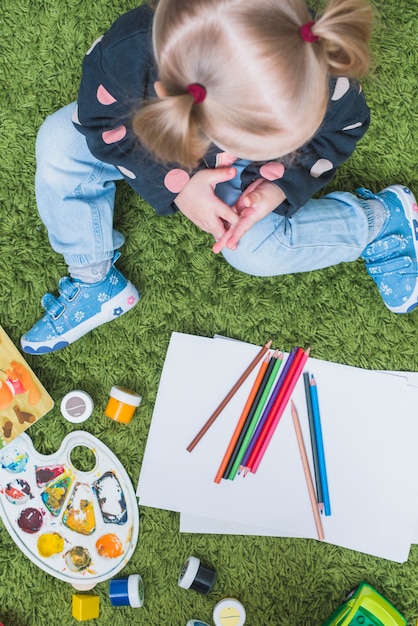 Little girl on carpet with pencils 