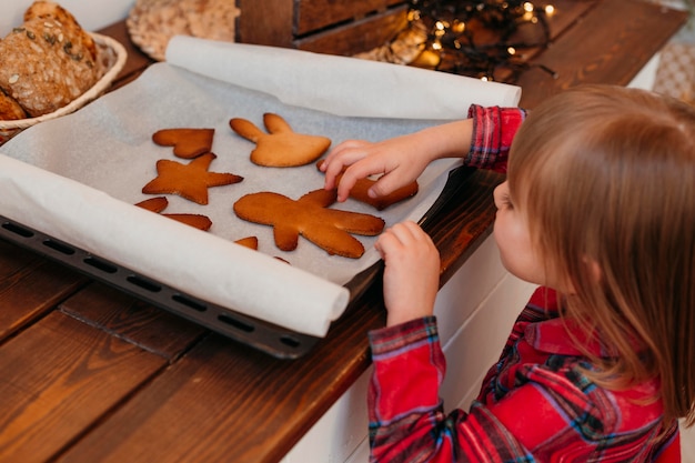 Free photo little girl checking baked christmas cookies