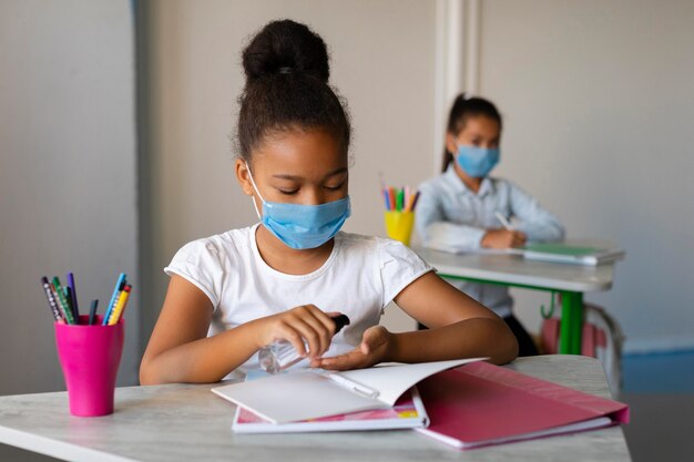 Little girl disinfecting her hands in class