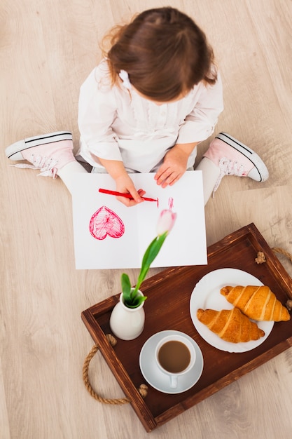 Free photo little girl drawing heart near tray with coffee