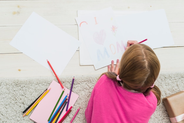 Free photo little girl drawing i love mom on paper