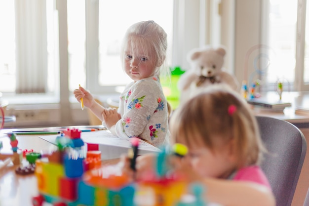 Free photo little girl drawing sitting at table