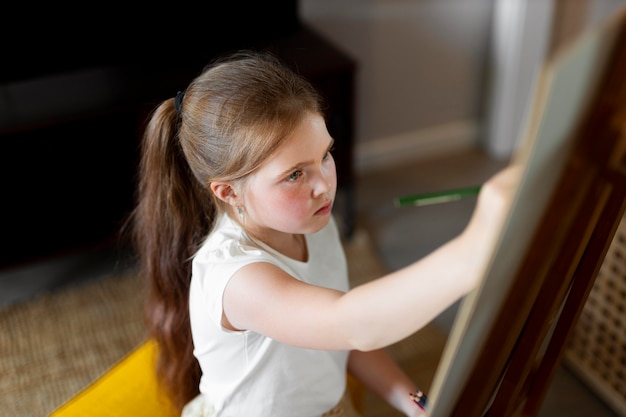 Little girl drawing using easel