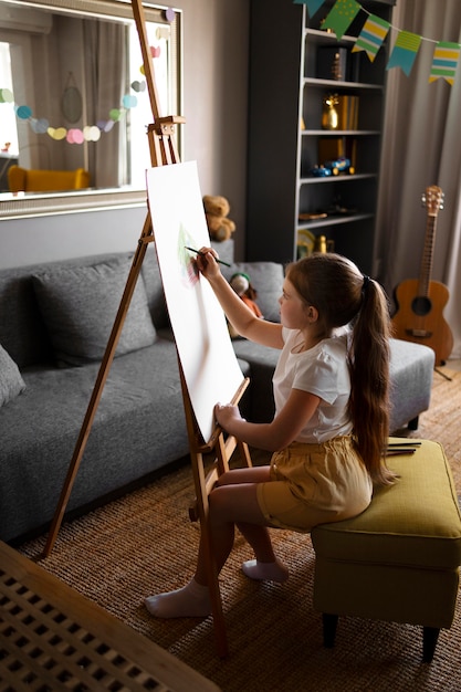 Little girl drawing using easel