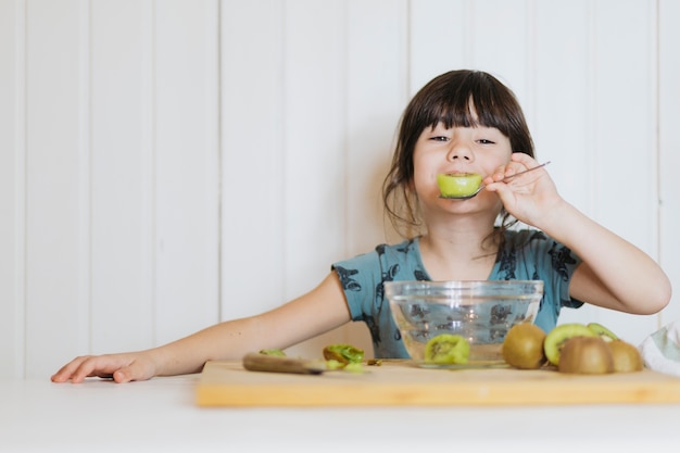 Free photo little girl eating kiwifruit