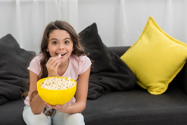 Little girl eating popcorn on the couch