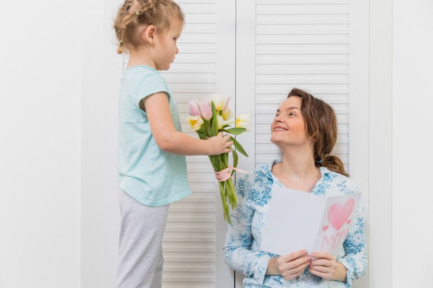 Free photo little girl giving flower bouquet to her mother on mother's day