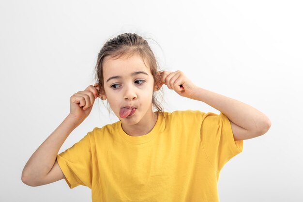 The little girl grimace holding her ears and sticking out her tongue