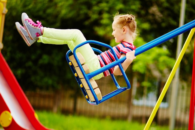 Little girl having fun on a swing outdoor