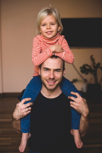 Free photo little girl on her father's shoulders with arms on his head