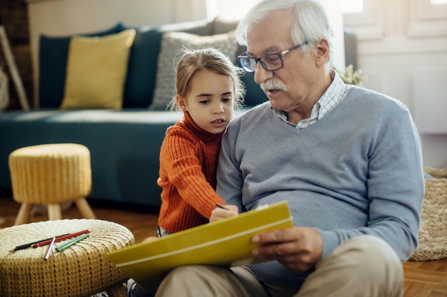 Little girl and her grandfather enjoying in creative time at home