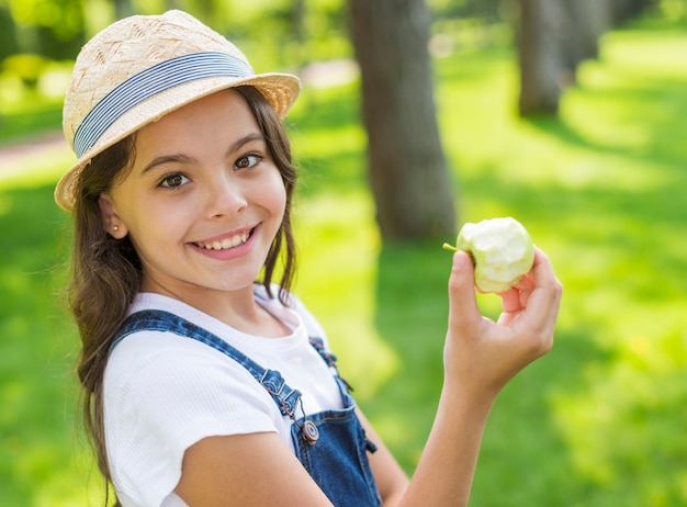 Little girl holding an apple while looking at the camera