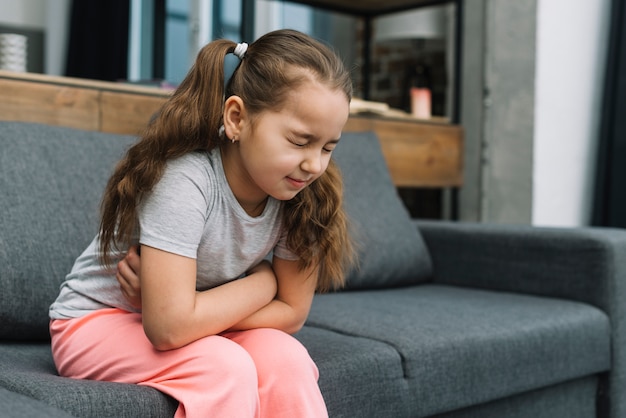 Little girl holding hands on her stomach suffering from pain