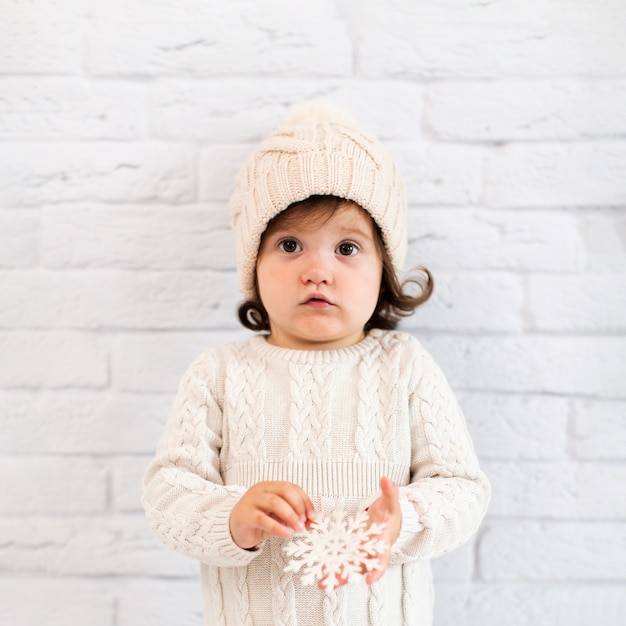 Free photo little girl holding a snowflake and looking at photographer