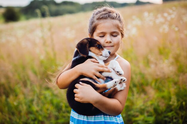 Little girl holds a puppy on her arms 