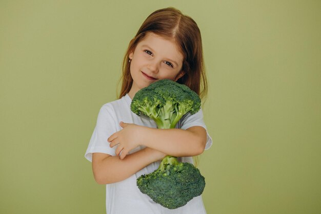 Little girl isolated holding green raw broccoli