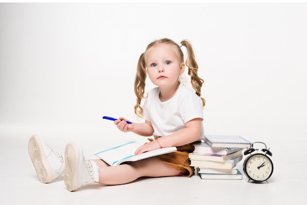 Free photo little girl laying on the floor and drawing pictures in a notebook isolated