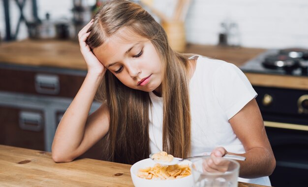 Little girl looking at her bowl with cereal