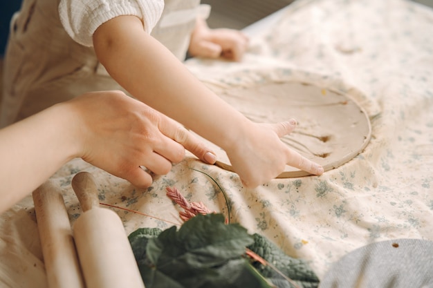 Little girl makes a clay plate and decorates it