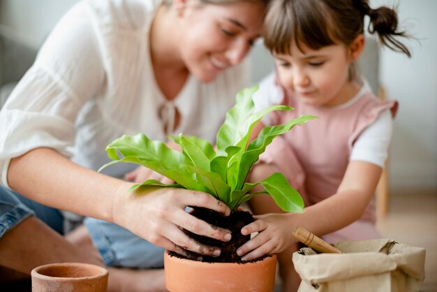 Little girl and mom potting plants at home