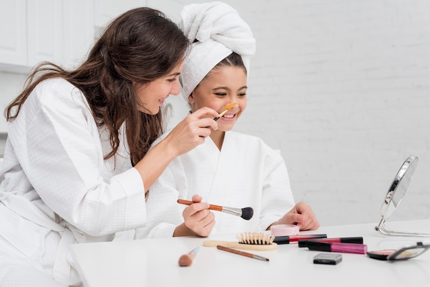 Free photo little girl and mother doing their make-up together