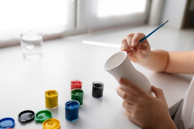 Little girl painting vase at home