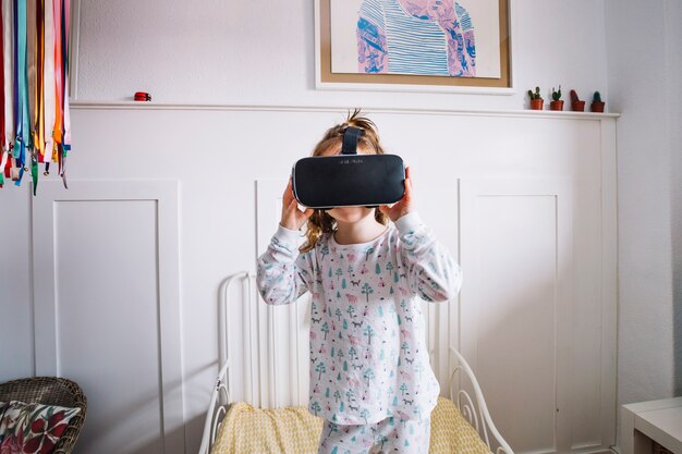 Little girl in pajamas and VR goggles