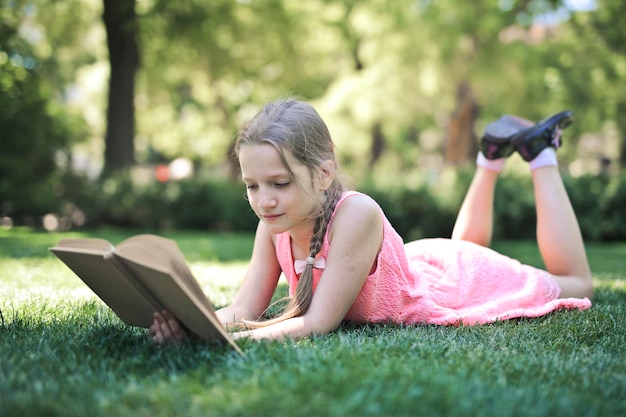 little girl in a park reads a book