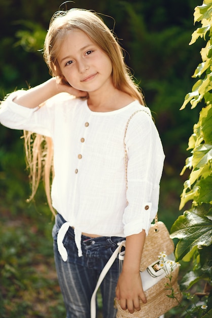 Little girl in a park standing with brown bag