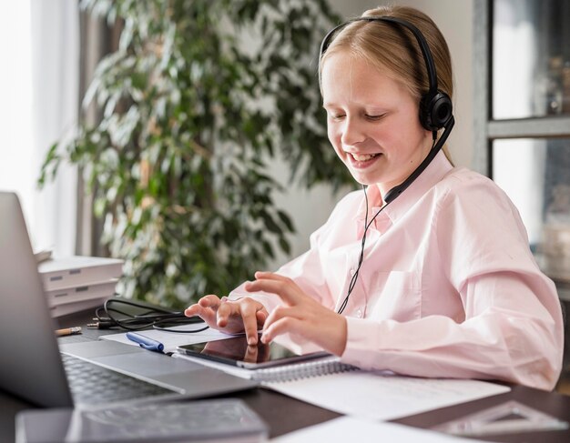 Little girl participating in online class while using tablet