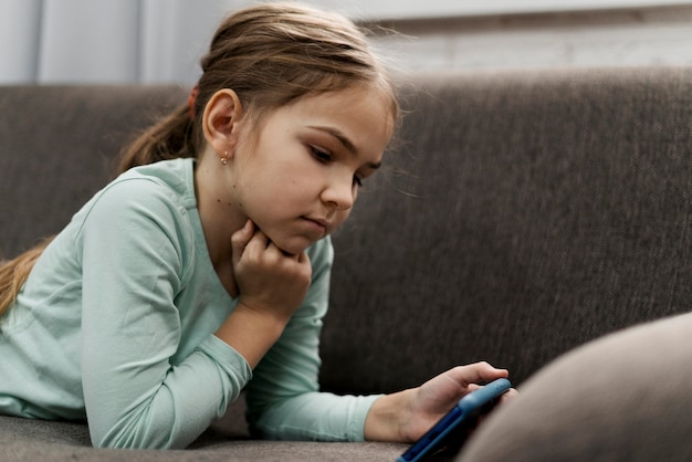 Little girl playing on a smartphone at home