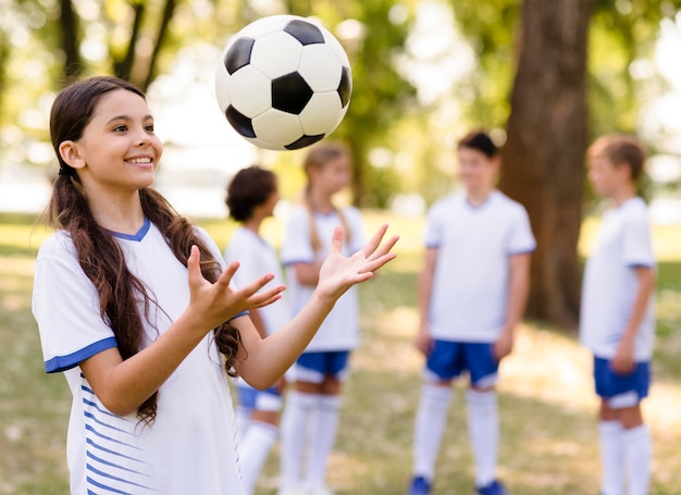 Little girl playing with a football outside