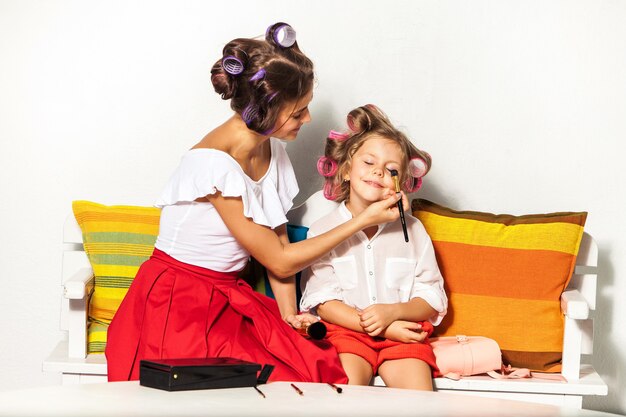 Little girl playing with her mom's makeup on white