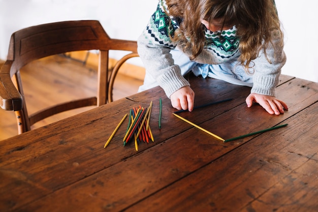 Free photo little girl playing with multi colored plastic sticks