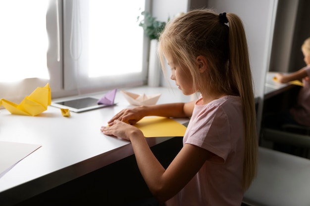 Little girl playing with origami paper at home