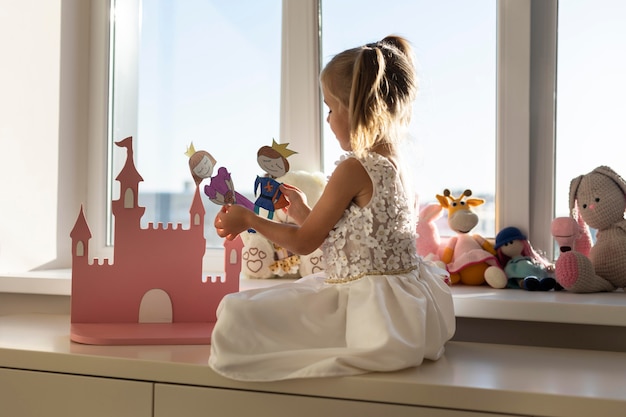 Free photo little girl playing with puppets at home