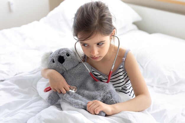 A little girl plays doctor with her favorite soft toy