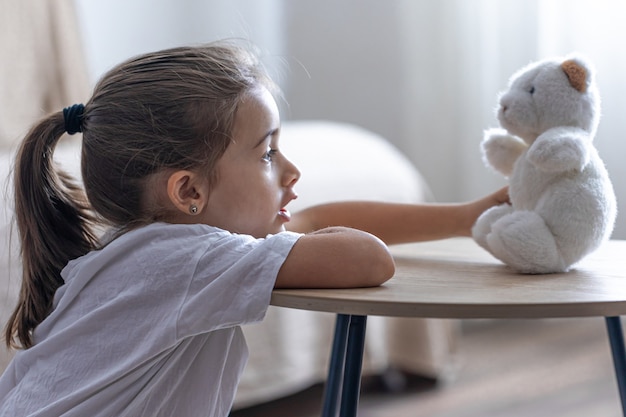 Free photo a little girl plays with her teddy bear.