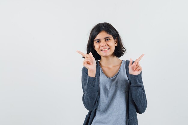 Little girl pointing up in t-shirt, jacket and looking merry