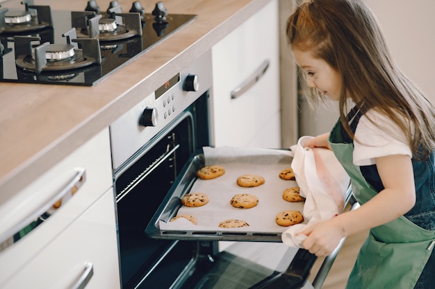 Free photo little girl pulls a cookie tray from the oven