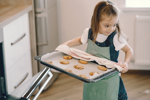 Little girl pulls a cookie tray from the oven