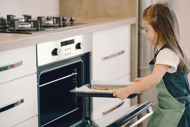 Little girl pulls a cookie tray from the oven