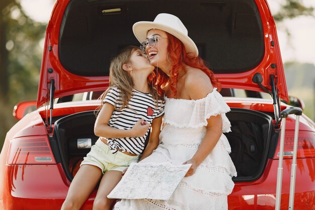 Little girl ready to go on vacations. Mother with daughter examining a map. Traveling by car with kids.