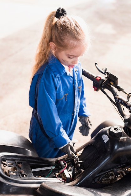 Little girl repairing  bike with spanner 